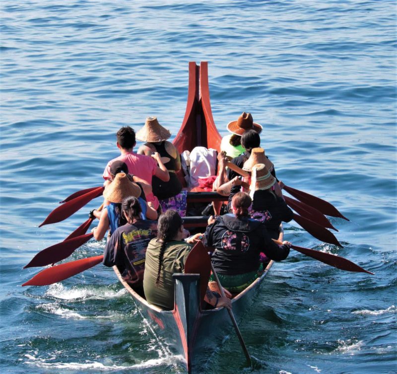 Canoe with tribal members heading out to sea
