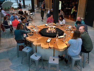 Group gathers around wood table firepit