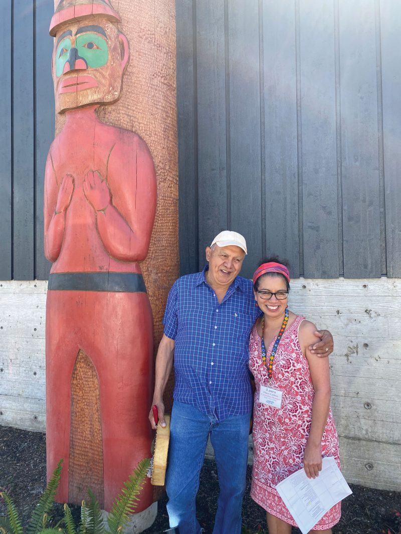 Man and woman standing in front of totem pole