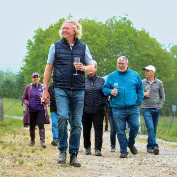 Man with glass of wine leads group at winery