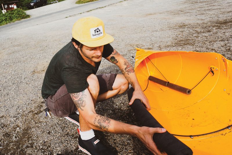 Man with hat repairing kayak