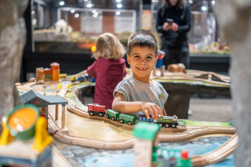 Grinning boy plays with trains at Imagine Childrens musems