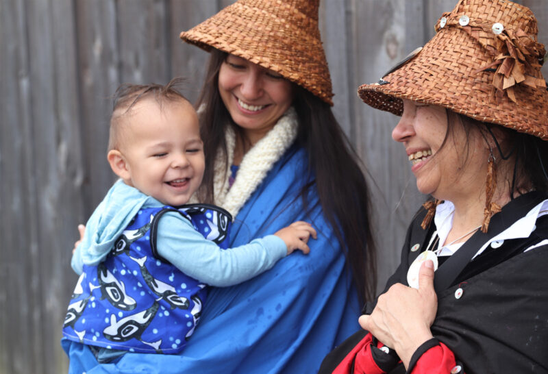 Three generations native Americans enjoy tribal salmon ceremony wearing cedar hats