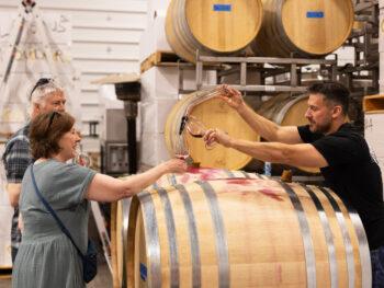 Wine sampling over wine barrels at winery