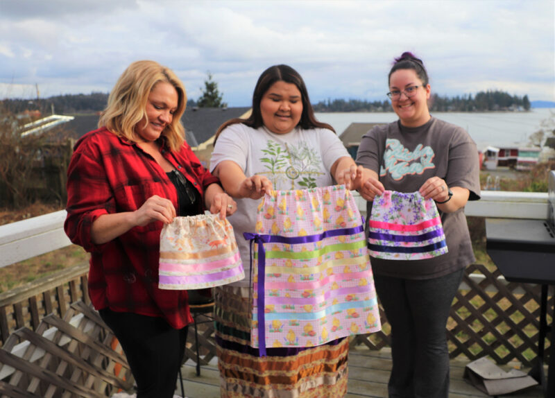 Nina Gobin and two participants of her ribbon making workshop display hand crafted creations