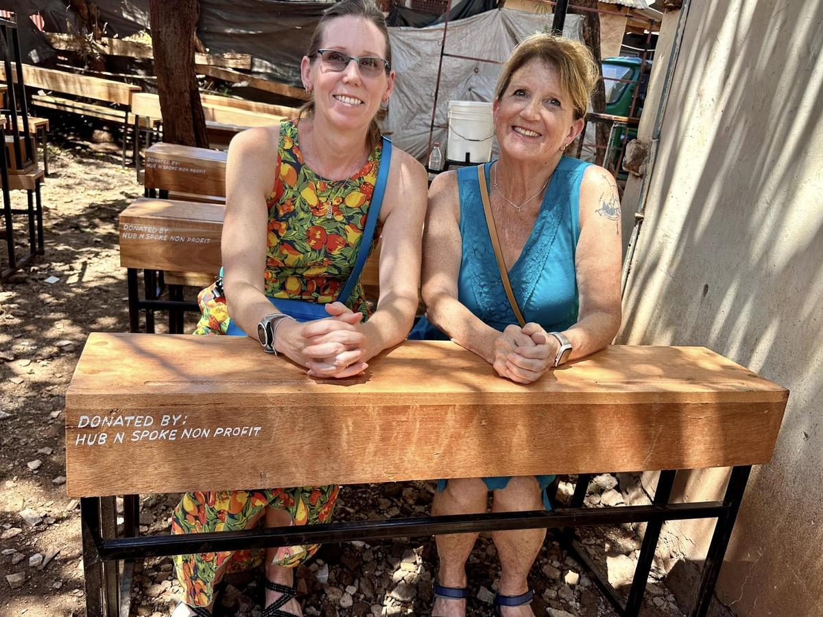 Michele Street sits with Tonya at a desk they provided for schools